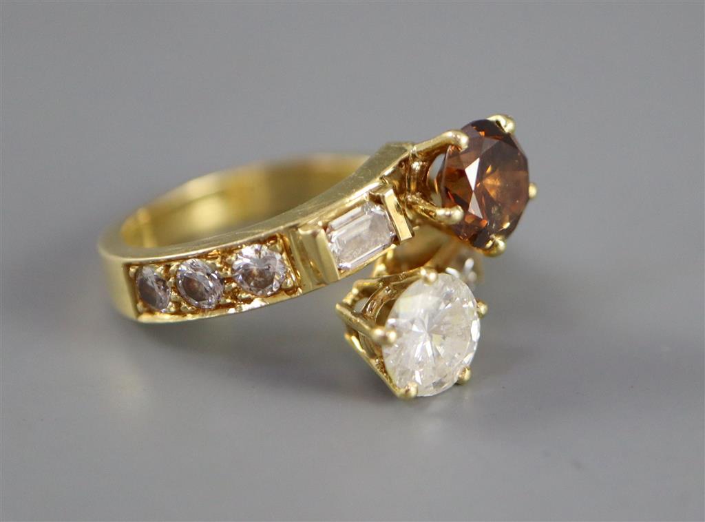 A modern yellow metal and two colour diamond two stone crossover ring,